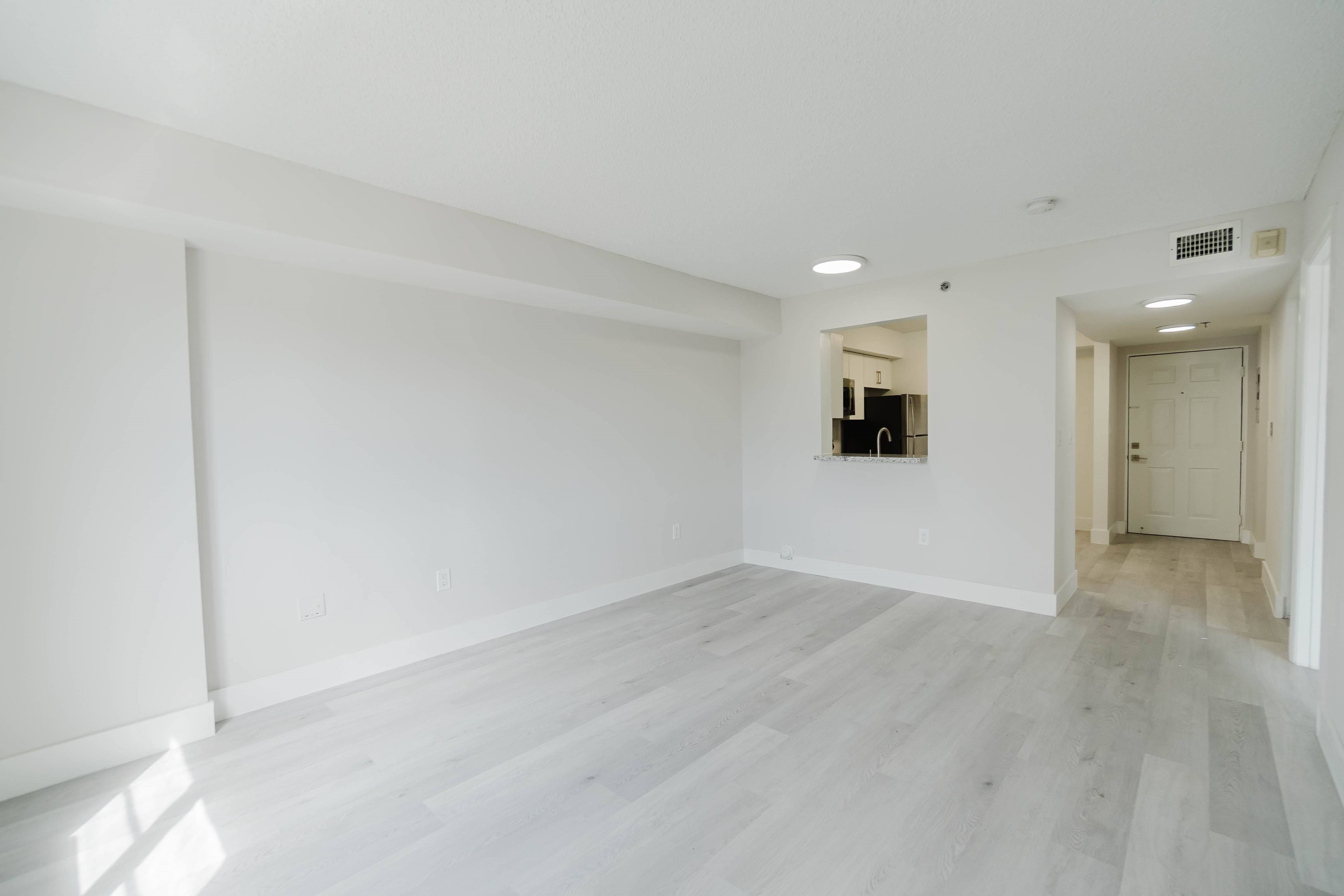 A spacious room with white walls and a wooden floor.